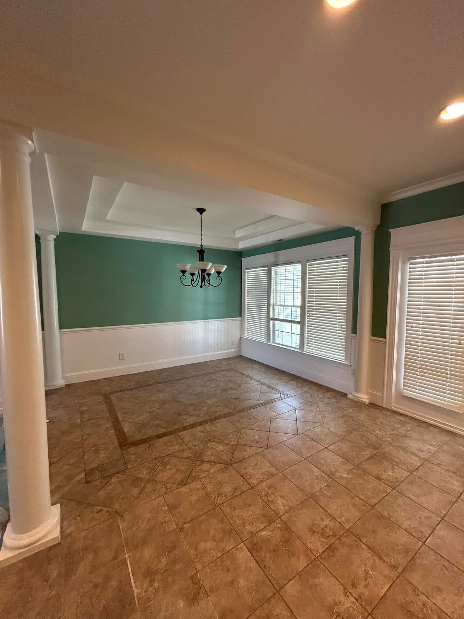 Dining room with teal accent walls, tray ceiling, and white wainscoting by Tacho Painting LLC